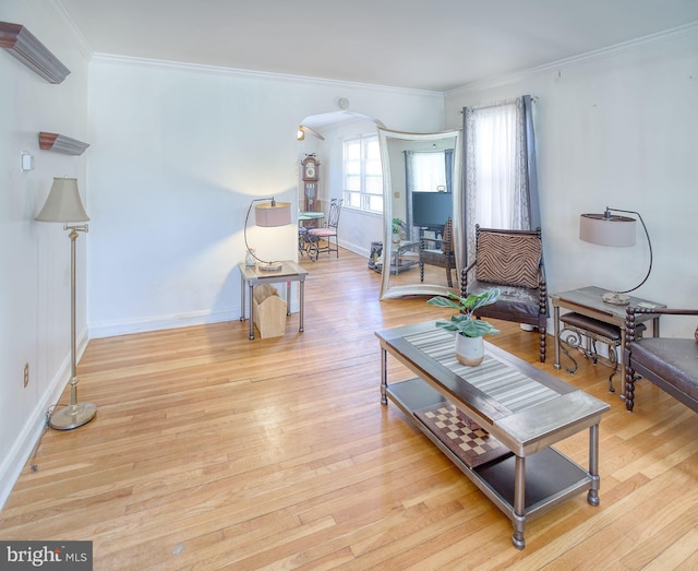 living area with baseboards, arched walkways, wood finished floors, and crown molding