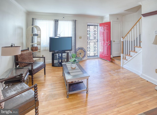 living room featuring stairs, baseboards, crown molding, and hardwood / wood-style flooring