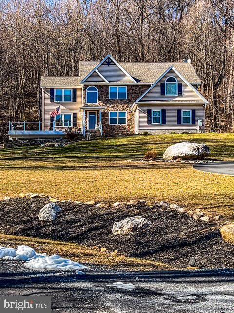 view of front of home featuring stone siding, a front lawn, and a chimney