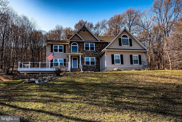 view of front of home featuring stone siding, a front lawn, and a wooden deck