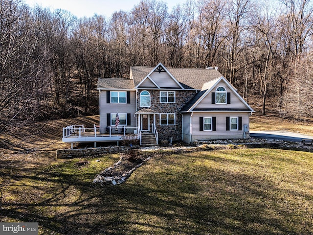 view of front facade featuring a chimney, stone siding, a wooden deck, and a front lawn