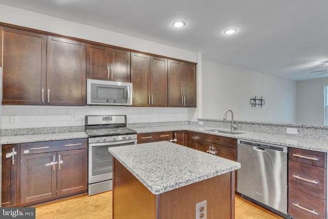 kitchen featuring backsplash, light wood-style flooring, stainless steel appliances, and a sink