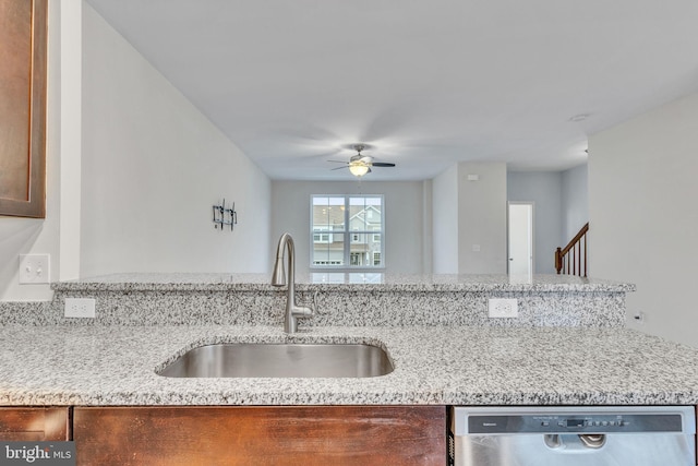 kitchen with light stone counters, dishwasher, a sink, and ceiling fan