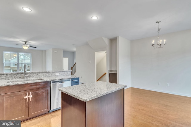 kitchen featuring dishwasher, a sink, light wood-style flooring, and light stone countertops