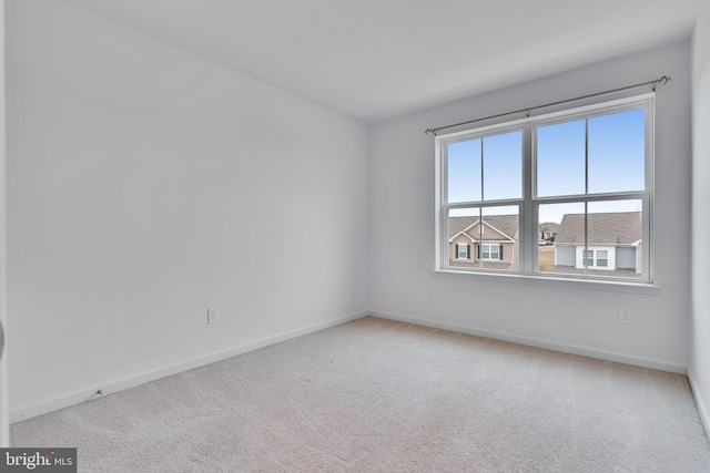 carpeted empty room featuring baseboards