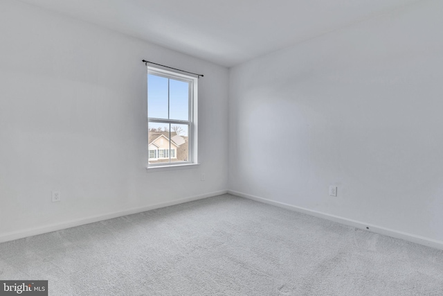 carpeted empty room featuring baseboards