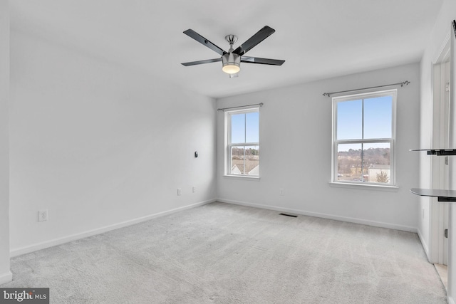 spare room featuring carpet floors, visible vents, baseboards, and a ceiling fan