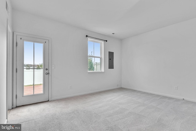 carpeted spare room featuring electric panel, plenty of natural light, and baseboards