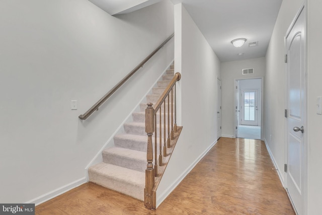 entryway with light wood-style floors, baseboards, stairway, and visible vents