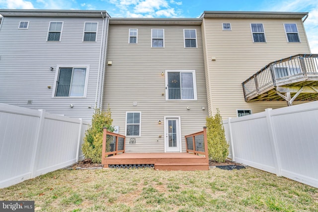 back of property with a fenced backyard, a lawn, and a deck