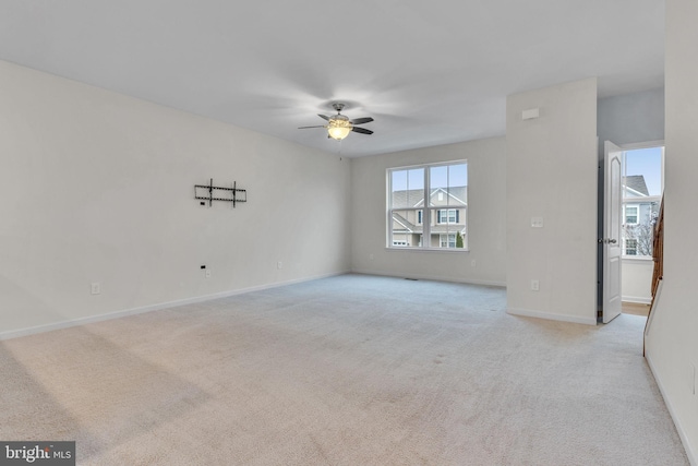 spare room with light carpet, ceiling fan, and baseboards