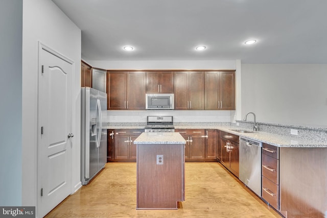 kitchen featuring light wood-type flooring, stainless steel appliances, a sink, and a center island