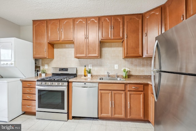 kitchen with a sink, stainless steel appliances, stacked washer and clothes dryer, and decorative backsplash