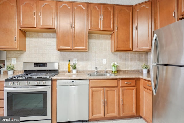 kitchen with light countertops, decorative backsplash, appliances with stainless steel finishes, brown cabinetry, and a sink