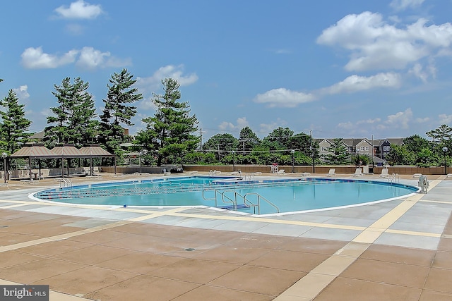 community pool with a gazebo, fence, and a patio