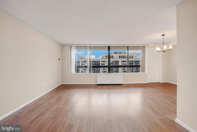 spare room featuring a textured ceiling, an inviting chandelier, and wood finished floors