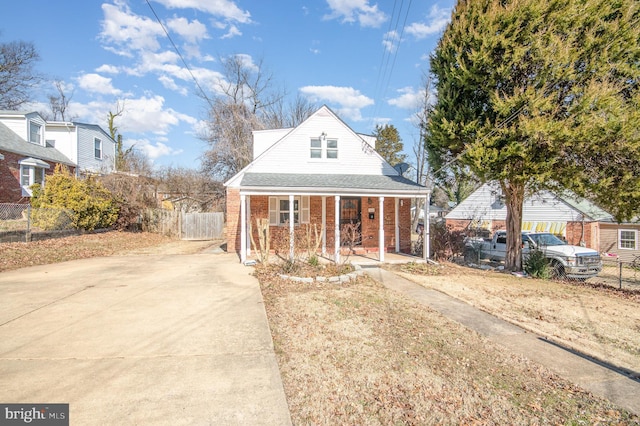 bungalow with a porch, brick siding, fence, and driveway