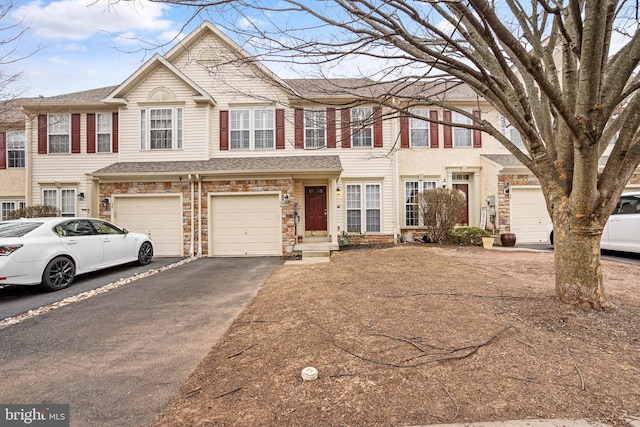 townhome / multi-family property with driveway, stone siding, and an attached garage