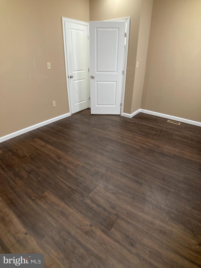 unfurnished room with dark wood finished floors and baseboards