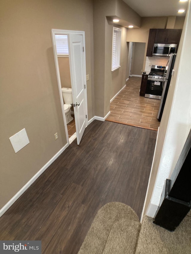 interior space with dark brown cabinetry, baseboards, appliances with stainless steel finishes, and wood finished floors