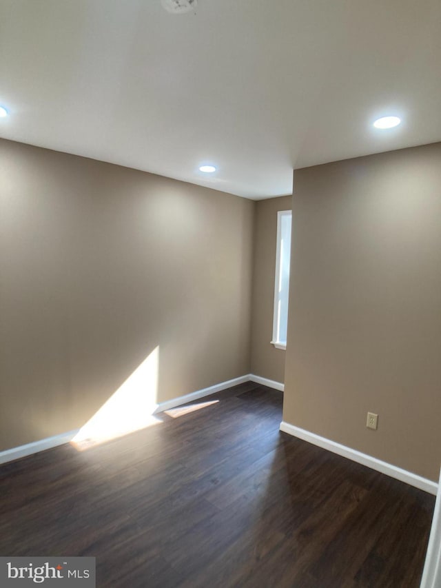 empty room featuring recessed lighting, dark wood-style flooring, and baseboards