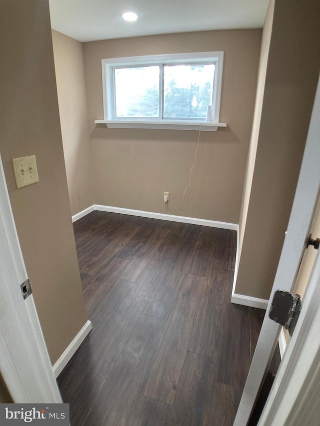 unfurnished bedroom with multiple windows, dark wood finished floors, and baseboards