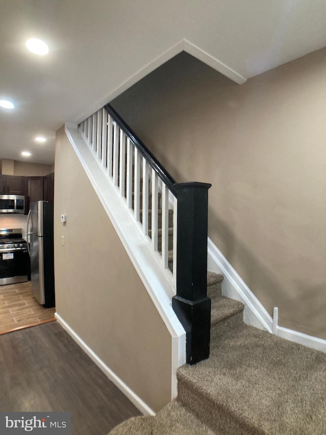 staircase with recessed lighting, baseboards, and wood finished floors