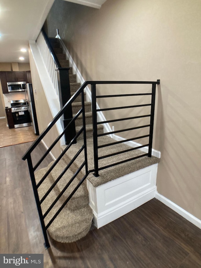 staircase featuring wood finished floors and baseboards