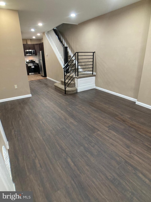 basement with stairs, baseboards, dark wood-type flooring, and freestanding refrigerator