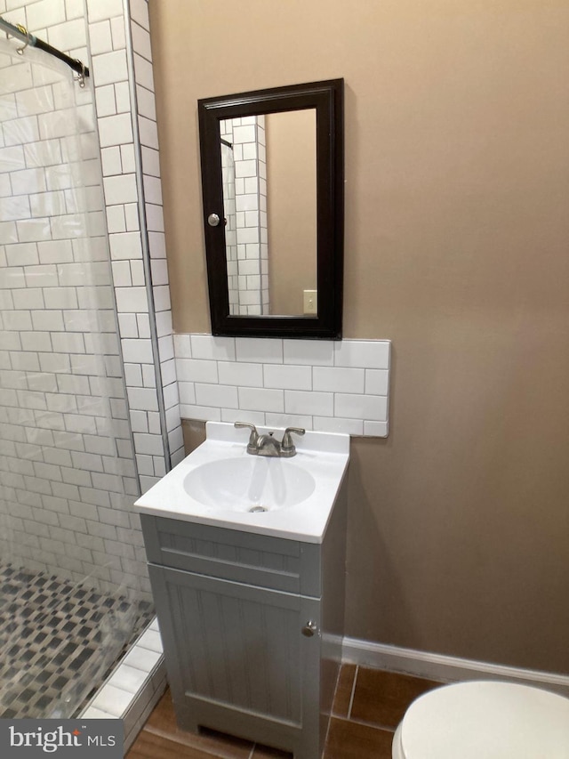 bathroom with tasteful backsplash, baseboards, toilet, vanity, and a shower stall