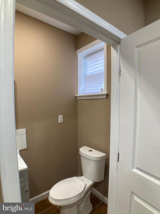 bathroom with toilet, baseboards, and vanity