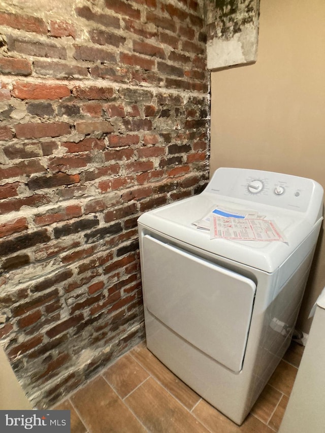 washroom featuring brick wall, washer / clothes dryer, and laundry area