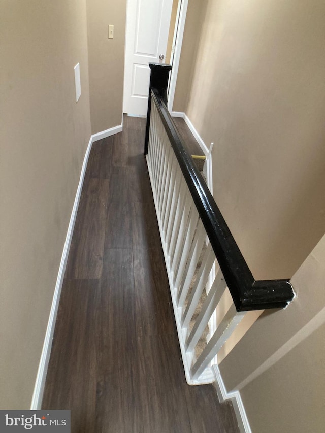 interior space featuring baseboards, dark wood-style flooring, and an upstairs landing