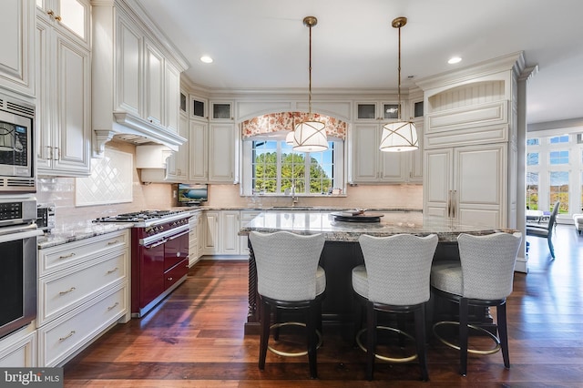 22577 Creighton Farms Dr, Leesburg, VA 20175 - kitchen with dark wood-style flooring, a kitchen island, light stone counters, and stainless steel appliances