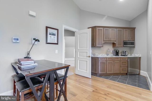 22577 Creighton Farms Dr, Leesburg, VA 20175 - kitchen featuring light wood-style flooring, refrigerator, stainless steel microwave, a sink, and light countertops