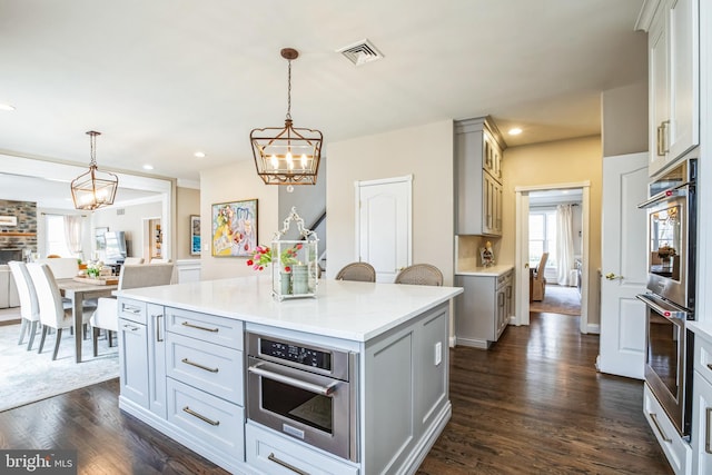 kitchen with a center island, pendant lighting, visible vents, and open floor plan