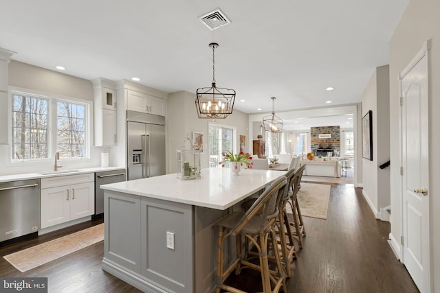 kitchen with a center island, light countertops, visible vents, appliances with stainless steel finishes, and a sink