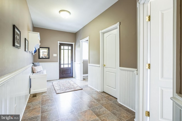 foyer with stone finish floor and wainscoting