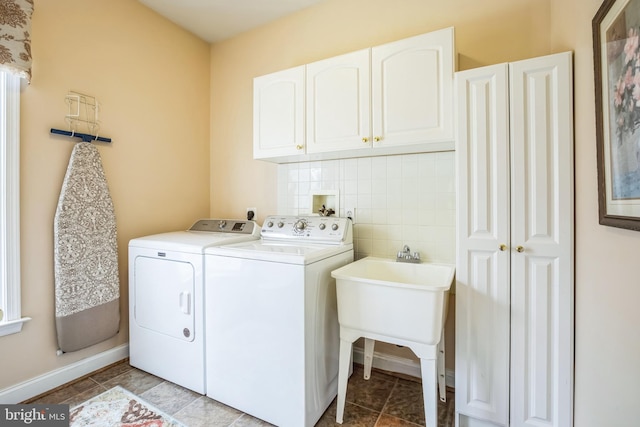 clothes washing area with cabinet space, baseboards, tile patterned floors, independent washer and dryer, and a sink