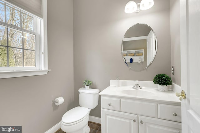 half bathroom with toilet, vanity, and baseboards