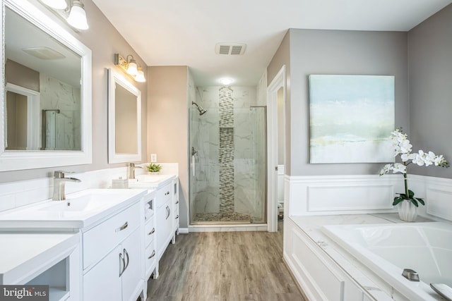 full bathroom with a stall shower, visible vents, a sink, and wood finished floors