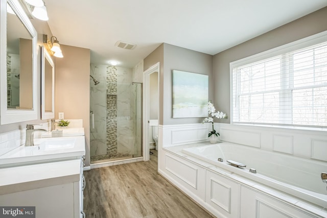 bathroom with a stall shower, visible vents, toilet, wood finished floors, and a bath