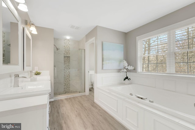 full bathroom featuring a stall shower, visible vents, wood finished floors, vanity, and a bath