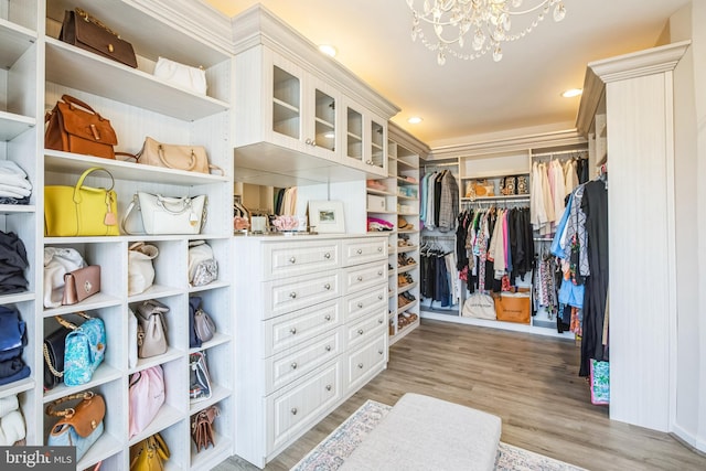 walk in closet with a notable chandelier and light wood finished floors