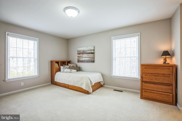 bedroom with baseboards, visible vents, and light colored carpet