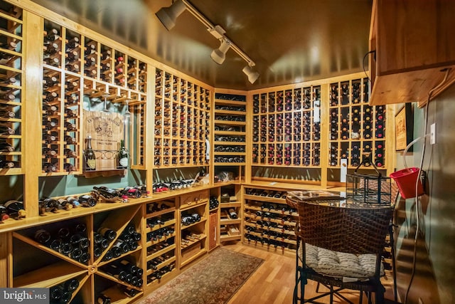 wine area featuring wood finished floors and track lighting