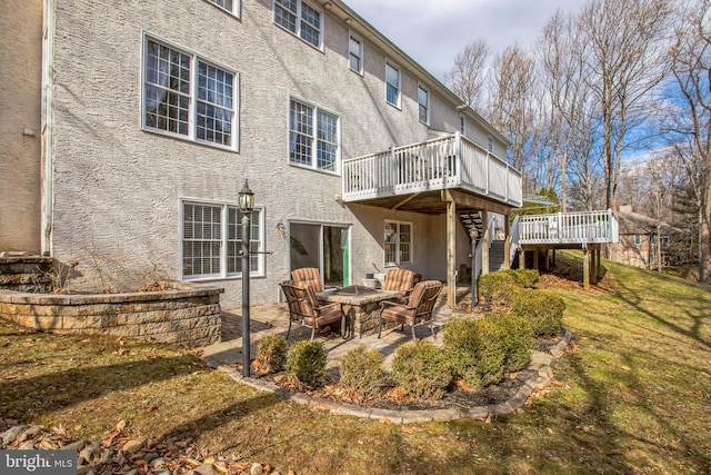 rear view of property with a deck, a patio, a fire pit, stairway, and stucco siding