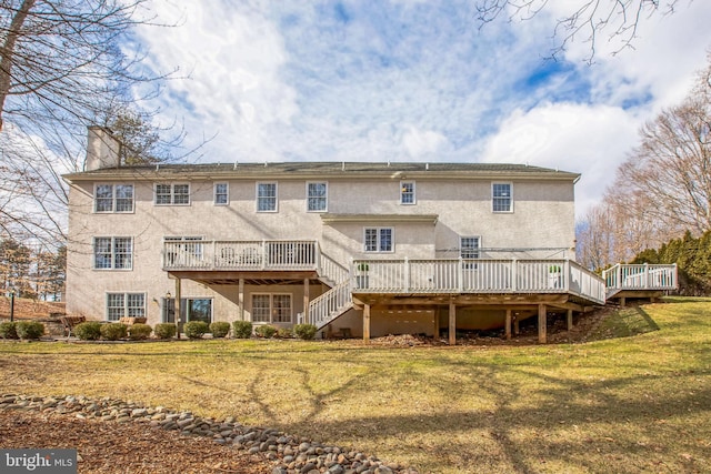 back of house featuring a chimney, stairway, a lawn, and a wooden deck