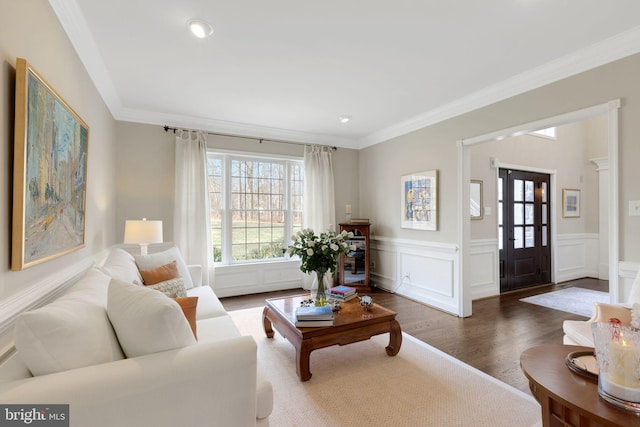 living area featuring ornamental molding, wainscoting, dark wood finished floors, and a decorative wall