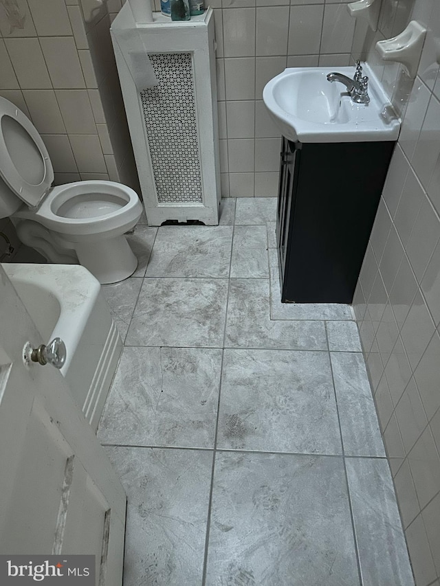 bathroom with toilet, tile walls, and vanity